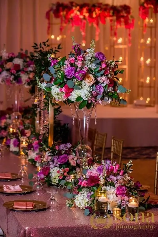 Reception detail of crystal chandeliers above floral centerpieces